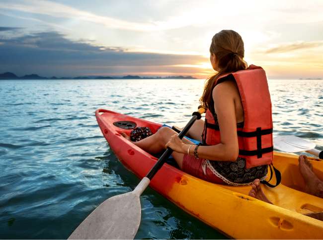 woman kayak on water sunset