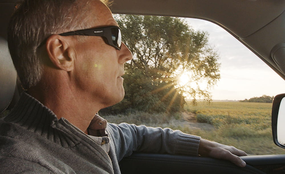 Older man driving with UV protection glasses after surgery